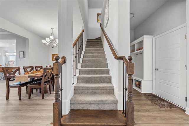 staircase with hardwood / wood-style flooring and a notable chandelier