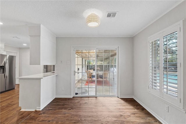 unfurnished dining area with crown molding, dark hardwood / wood-style flooring, and a textured ceiling