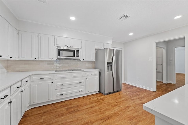 kitchen with white cabinetry, stainless steel appliances, decorative backsplash, and light wood-type flooring