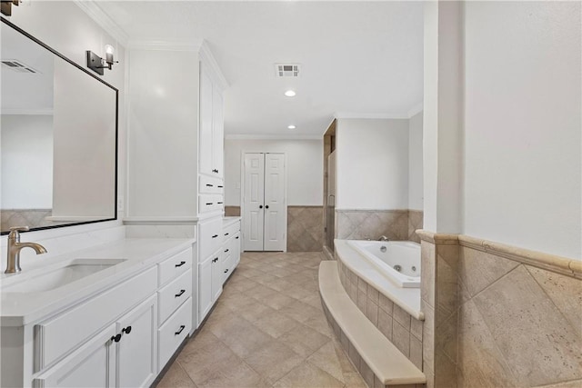 bathroom with crown molding, vanity, tile walls, and tiled tub