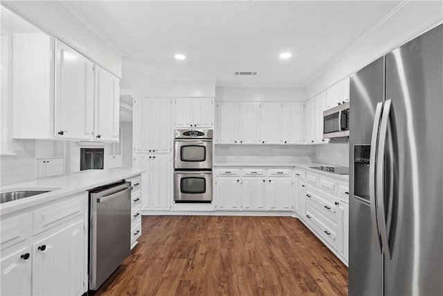 kitchen featuring appliances with stainless steel finishes, dark hardwood / wood-style floors, and white cabinets