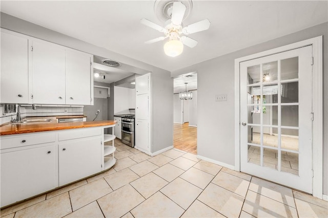 kitchen featuring butcher block countertops, backsplash, white cabinetry, and double oven range