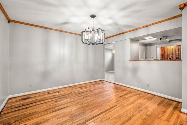 unfurnished dining area featuring crown molding, wood-type flooring, and a notable chandelier