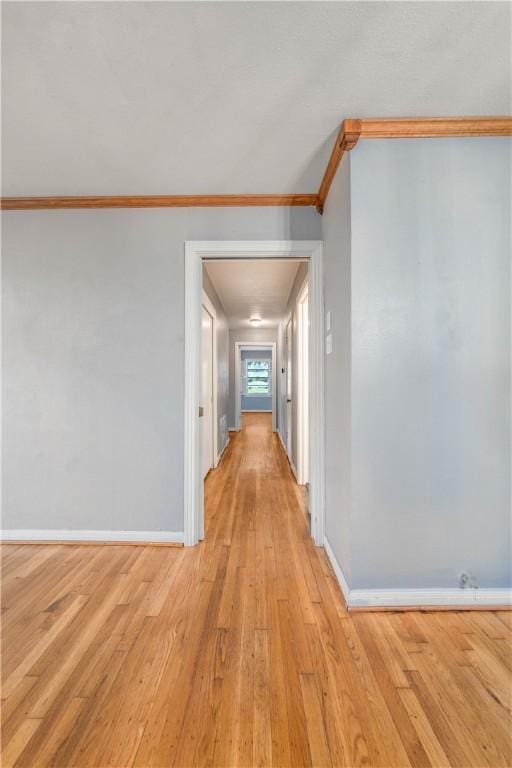 corridor with light hardwood / wood-style flooring and ornamental molding