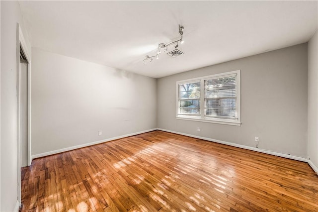 empty room with rail lighting and light wood-type flooring