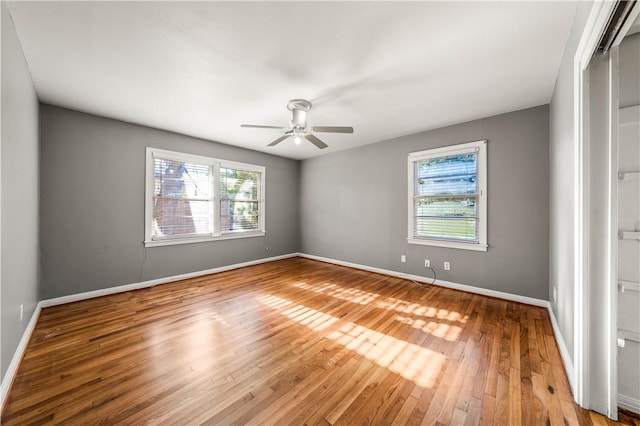 spare room with plenty of natural light, ceiling fan, and light wood-type flooring