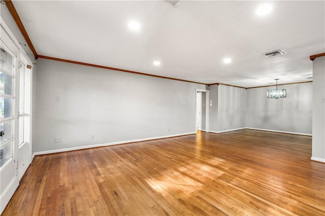 spare room with a notable chandelier, wood-type flooring, and crown molding