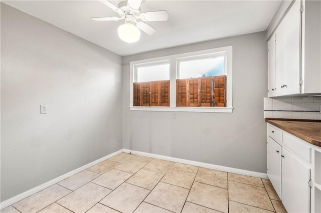 unfurnished dining area with ceiling fan and light tile patterned floors