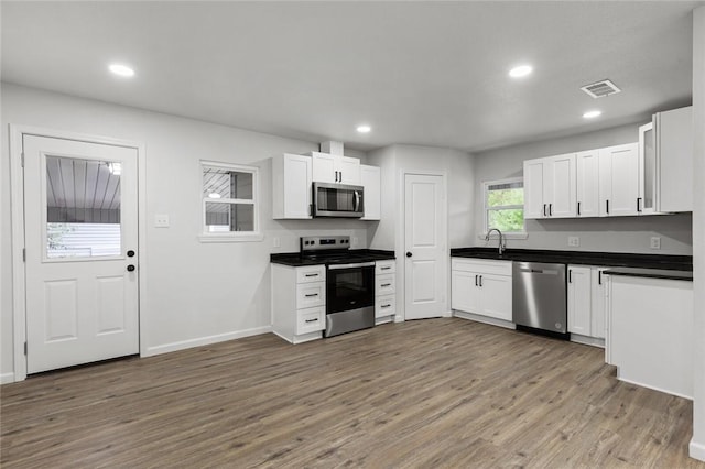 kitchen with dark hardwood / wood-style floors, white cabinetry, sink, and appliances with stainless steel finishes