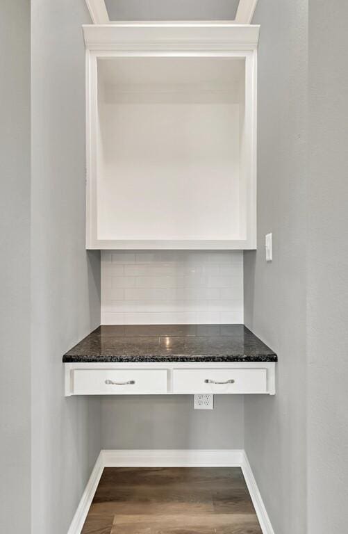 interior space featuring backsplash, white cabinetry, dark stone counters, and dark wood-type flooring