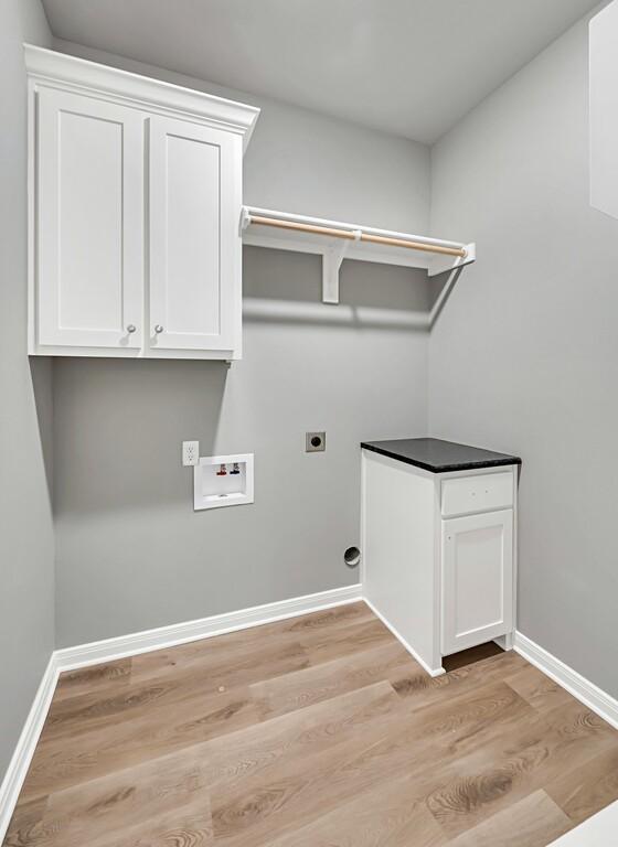 clothes washing area with washer hookup, hookup for an electric dryer, cabinets, and light hardwood / wood-style flooring