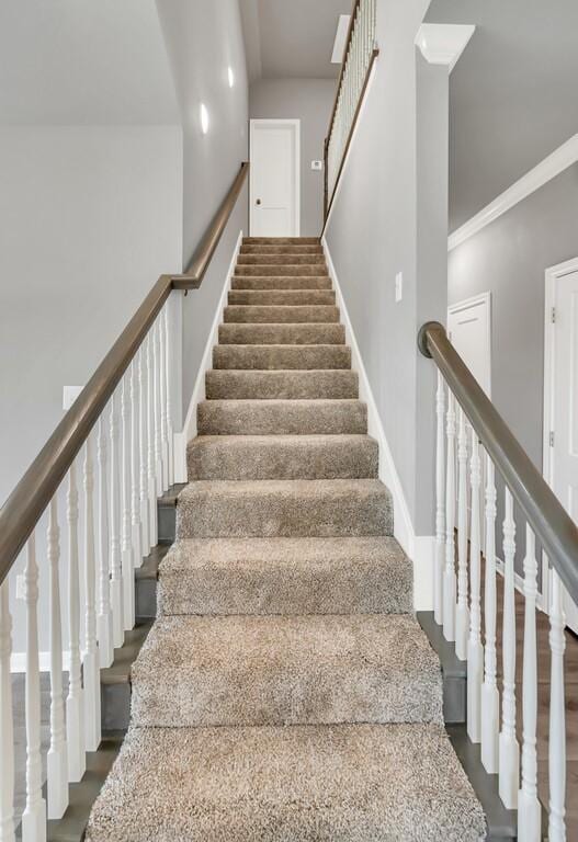 staircase with hardwood / wood-style floors and crown molding