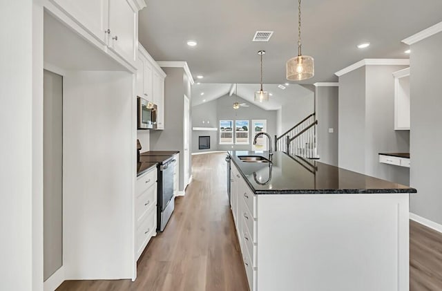 kitchen with appliances with stainless steel finishes, ceiling fan, a center island with sink, white cabinets, and hanging light fixtures