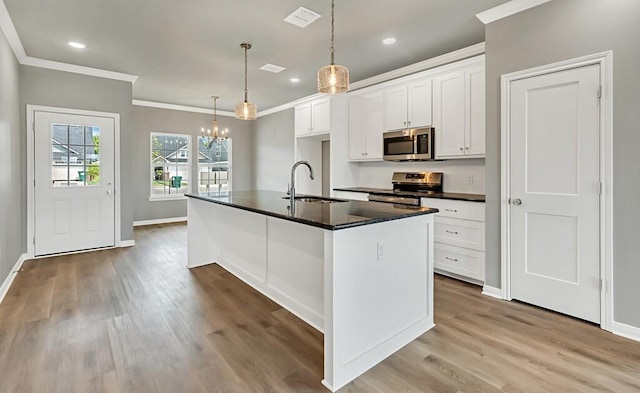 kitchen featuring pendant lighting, a kitchen island with sink, sink, appliances with stainless steel finishes, and white cabinetry