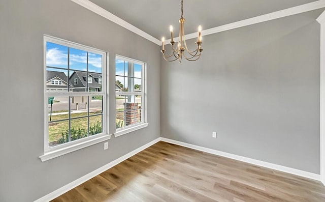 unfurnished room featuring a notable chandelier, plenty of natural light, wood-type flooring, and ornamental molding