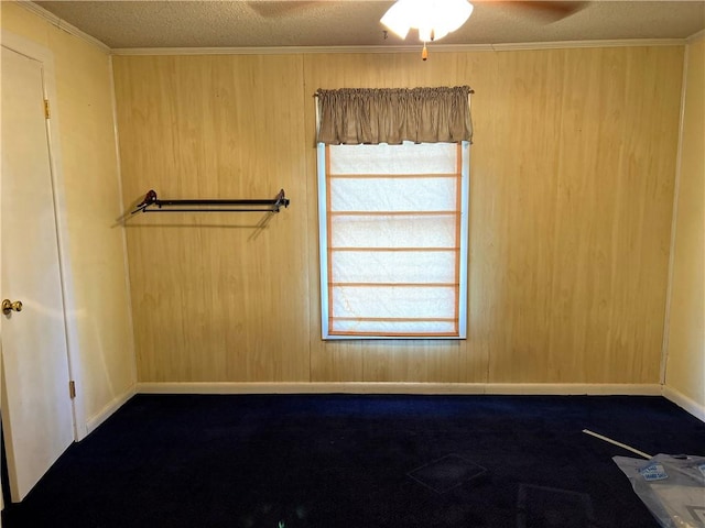 empty room featuring wooden walls, crown molding, ceiling fan, and a textured ceiling