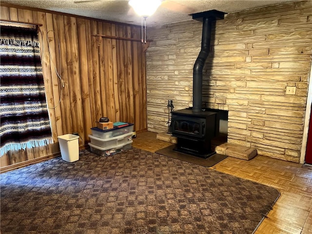 unfurnished living room with wooden walls, a textured ceiling, and parquet flooring