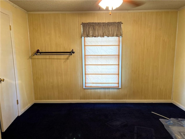 spare room with wood walls, crown molding, ceiling fan, and a textured ceiling