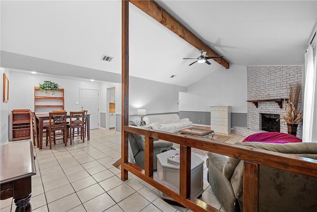 tiled living room featuring ceiling fan, vaulted ceiling with beams, and a fireplace