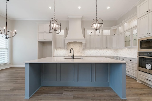 kitchen with a spacious island, white cabinetry, premium range hood, and appliances with stainless steel finishes