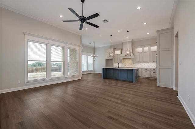 kitchen featuring plenty of natural light, an island with sink, decorative light fixtures, and custom range hood