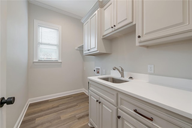 laundry room with sink, cabinets, light hardwood / wood-style flooring, crown molding, and hookup for a washing machine