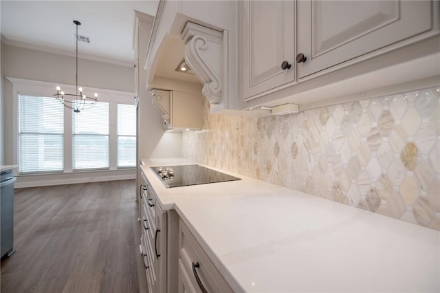 kitchen featuring black electric stovetop, backsplash, pendant lighting, a notable chandelier, and dark hardwood / wood-style floors