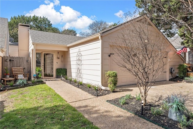 view of front of house with a garage, a chimney, roof with shingles, fence, and a front yard