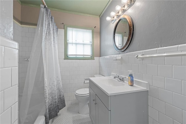 full bathroom with toilet, tile walls, ornamental molding, shower / bathtub combination with curtain, and vanity