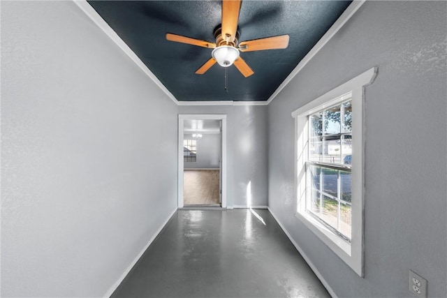 spare room featuring ceiling fan, ornamental molding, and concrete floors