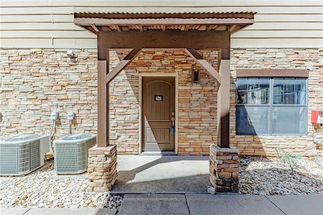 entrance to property with cooling unit and stone siding