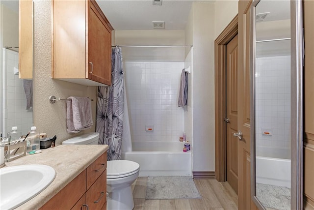 full bathroom featuring shower / bathtub combination with curtain, toilet, wood finished floors, vanity, and a textured wall