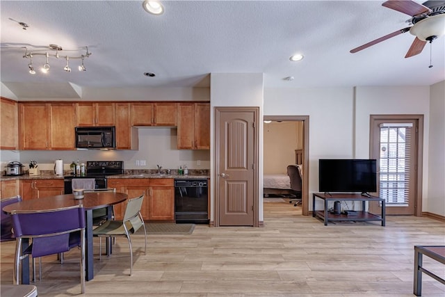 kitchen featuring brown cabinets, black appliances, a sink, recessed lighting, and light wood-style floors