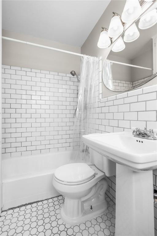 full bath featuring shower / bath combination with curtain, decorative backsplash, toilet, and tile walls