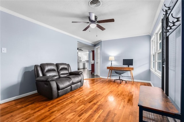 living room with a ceiling fan, wood finished floors, visible vents, baseboards, and ornamental molding