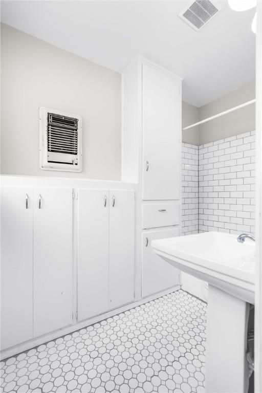 bathroom with tile patterned floors, visible vents, and an AC wall unit