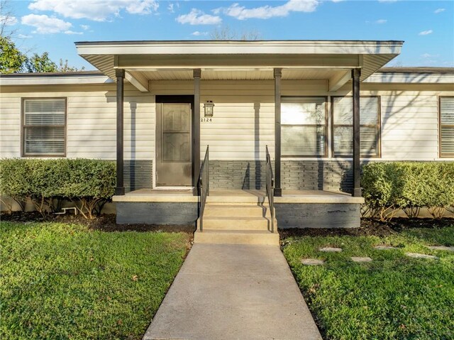 entrance to property with a yard and covered porch