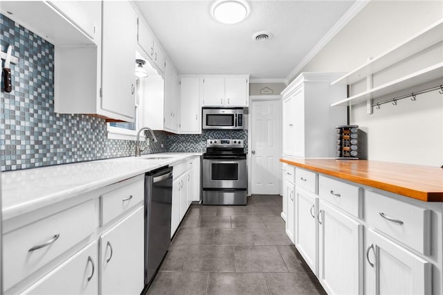 kitchen with visible vents, ornamental molding, decorative backsplash, appliances with stainless steel finishes, and a sink