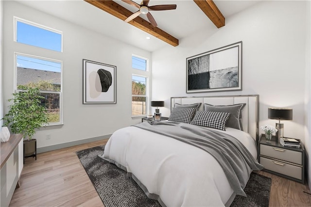 bedroom with beam ceiling, multiple windows, ceiling fan, and light hardwood / wood-style flooring