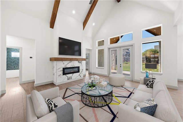 living room with beamed ceiling, light wood-type flooring, a fireplace, and high vaulted ceiling