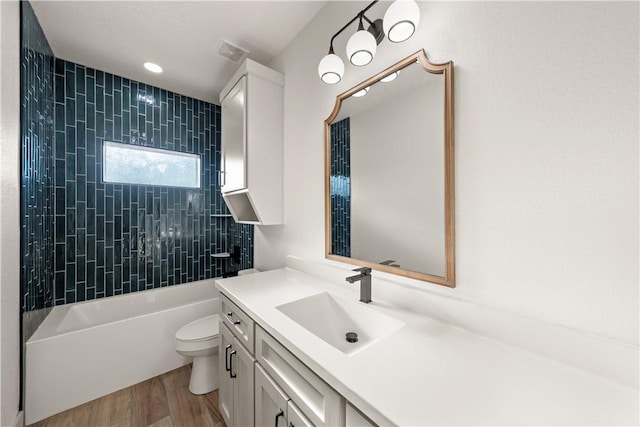 full bathroom with toilet, hardwood / wood-style floors, vanity, and tiled shower / bath