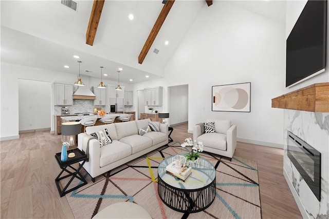 living room with beam ceiling, light hardwood / wood-style flooring, and high vaulted ceiling