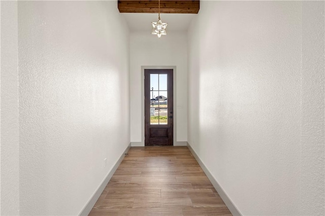 entryway with beamed ceiling, light hardwood / wood-style floors, and a notable chandelier