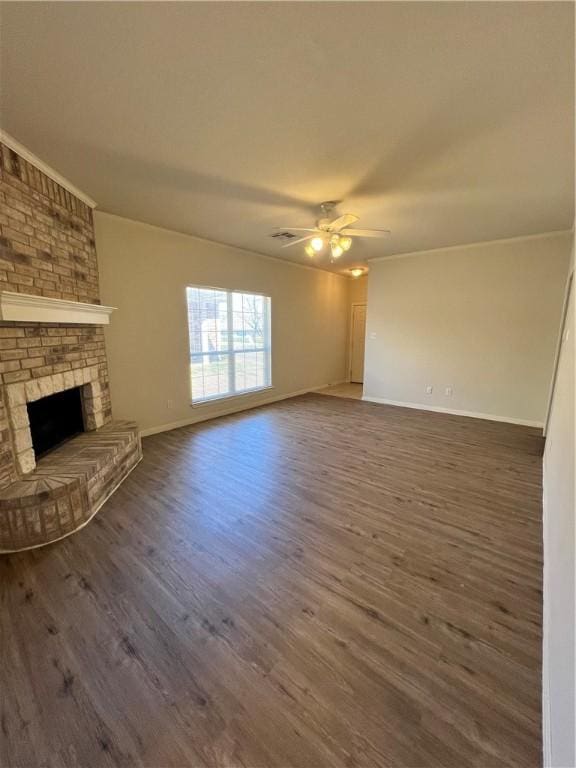 unfurnished living room featuring a brick fireplace, baseboards, dark wood-type flooring, and a ceiling fan