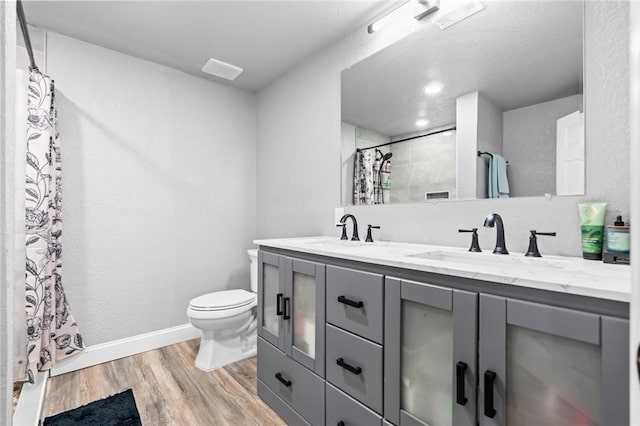 bathroom featuring curtained shower, hardwood / wood-style floors, vanity, and toilet