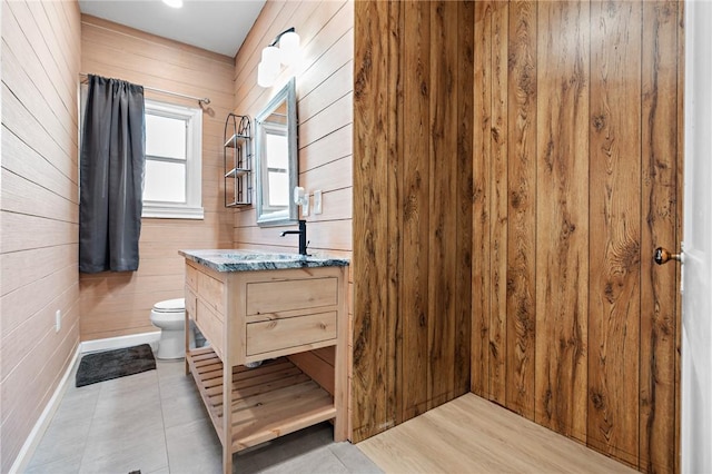 bathroom with wooden walls, vanity, wood-type flooring, and toilet