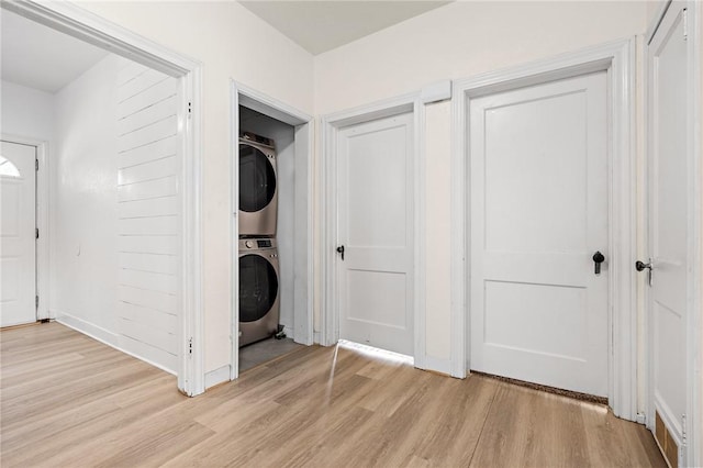 laundry room with light hardwood / wood-style flooring and stacked washing maching and dryer