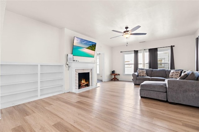 living room with ceiling fan, a fireplace, and light wood-type flooring