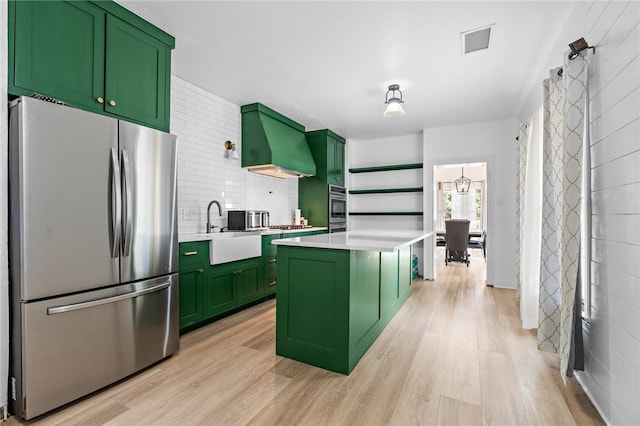 kitchen featuring a center island, stainless steel refrigerator, green cabinets, and sink