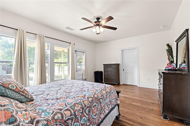 bedroom with access to outside, multiple windows, ceiling fan, and hardwood / wood-style flooring